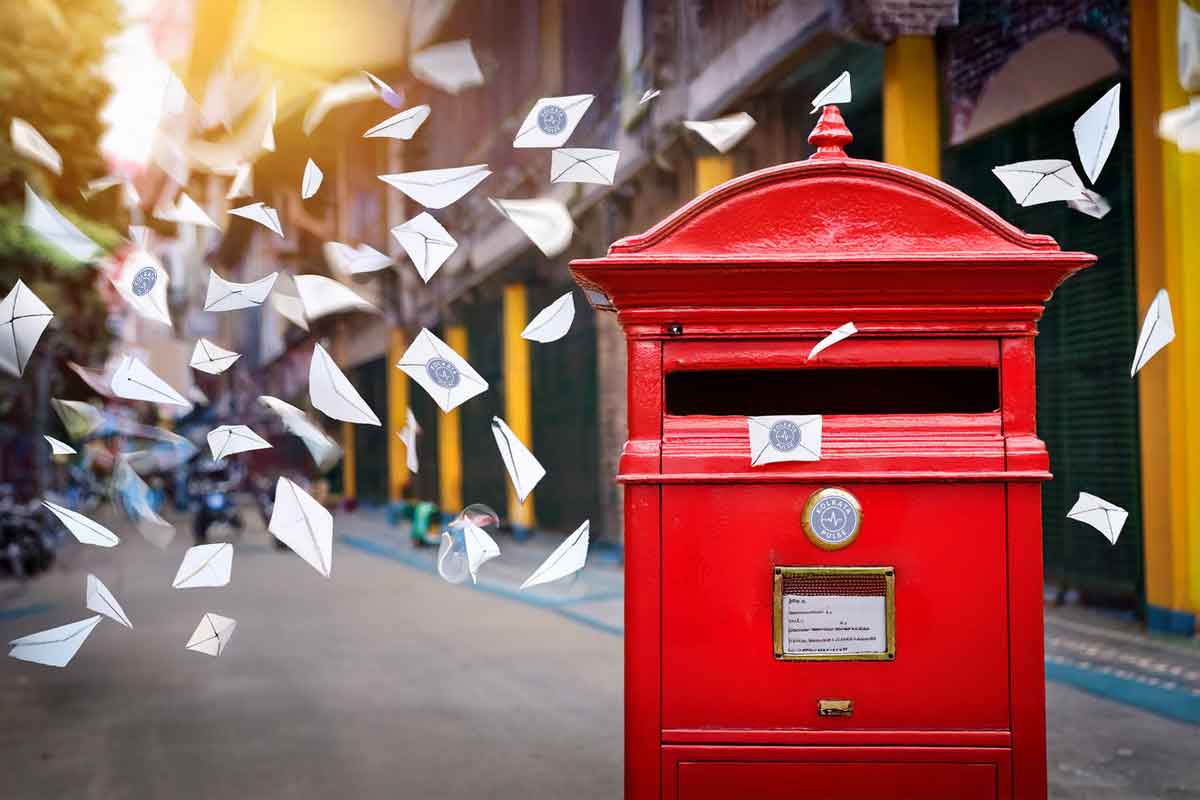 Red Kolkata letterbox with paper letters flying on a street in North Kolkata